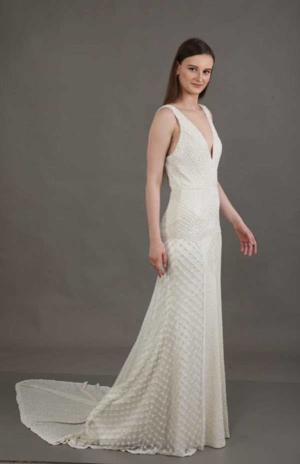 Woman wearing a white wedding dress with a long train on a gray background
